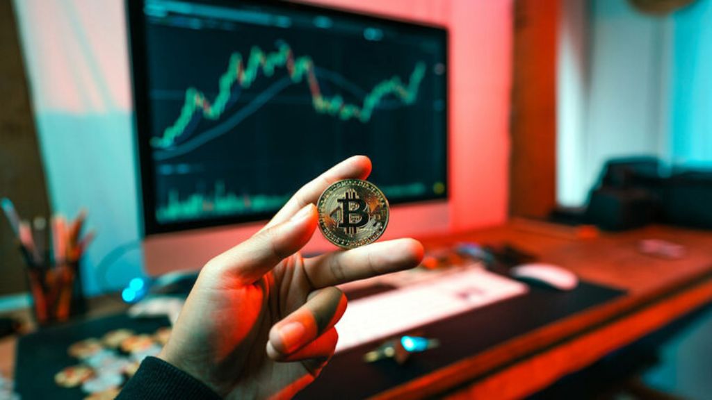 یک نماد بیت کوین در پیشزمینه یک چارت