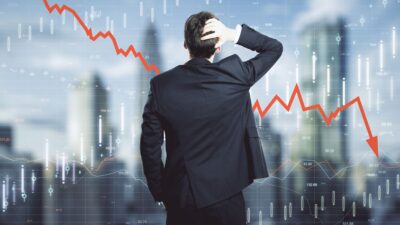 مردی دست به سر مشغول نگاه کردن به نمودار نزولی