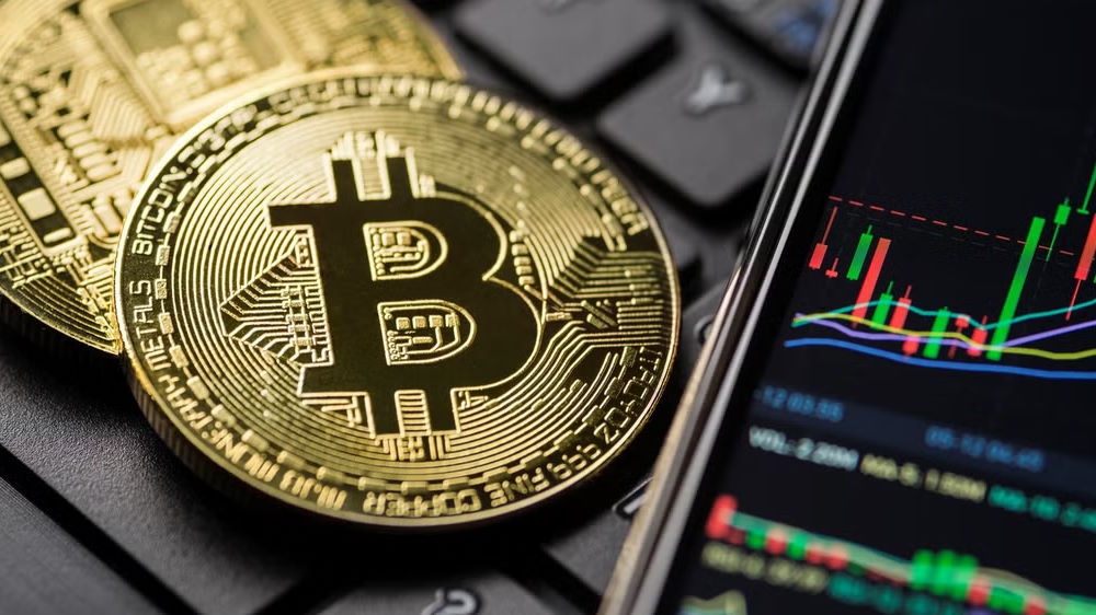 دو سکه بیت کوین در کنار گوشی با چارت