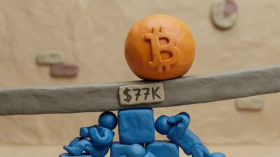لوگوی بیت کوین روی اهرم تعادل با برچسب قیمتی ۷۷ هزار دلار